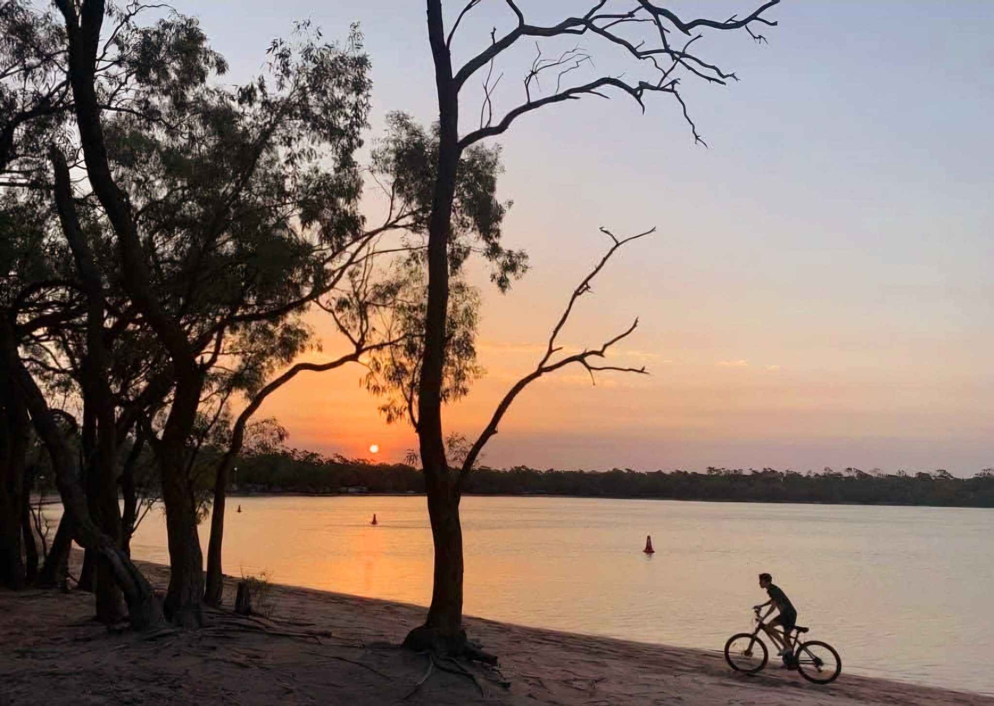 Sunset over Green Lake with trees and a cyclist by the shore